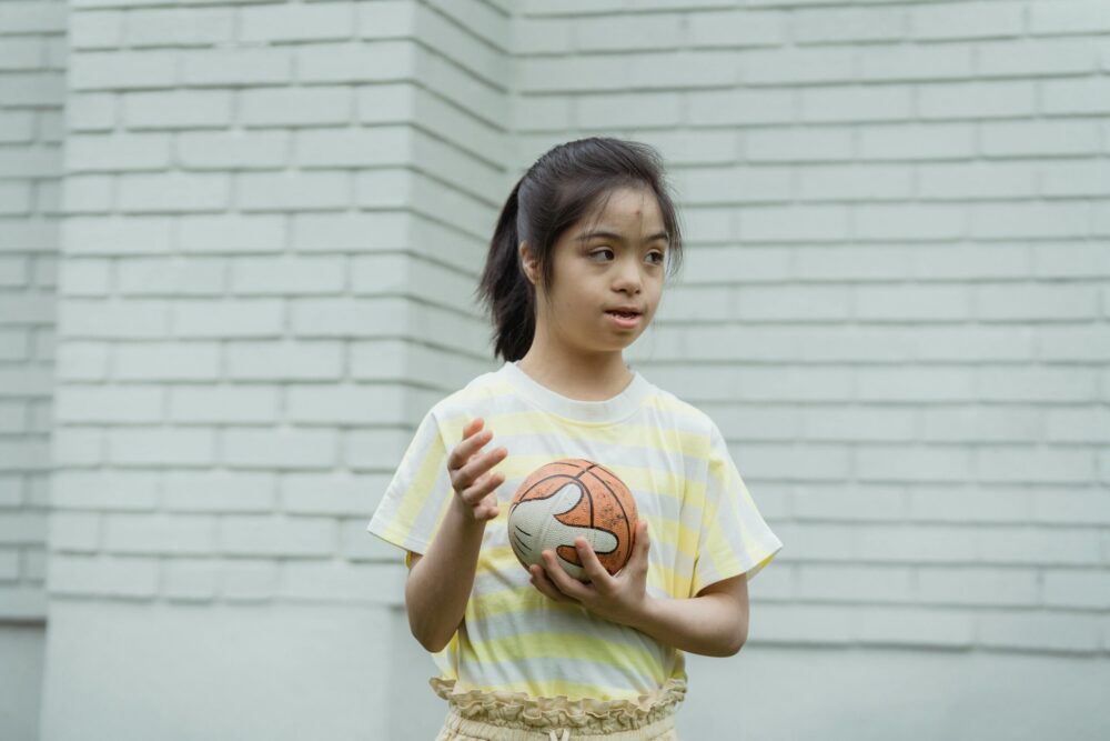 Girl in a striped shirt holding a ball.