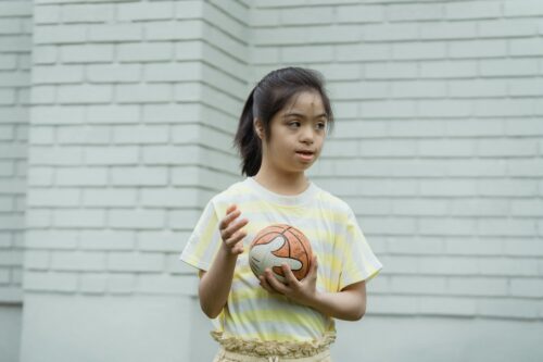 Girl in a striped shirt holding a ball.