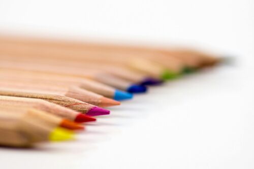 row of colored pencils against a white background