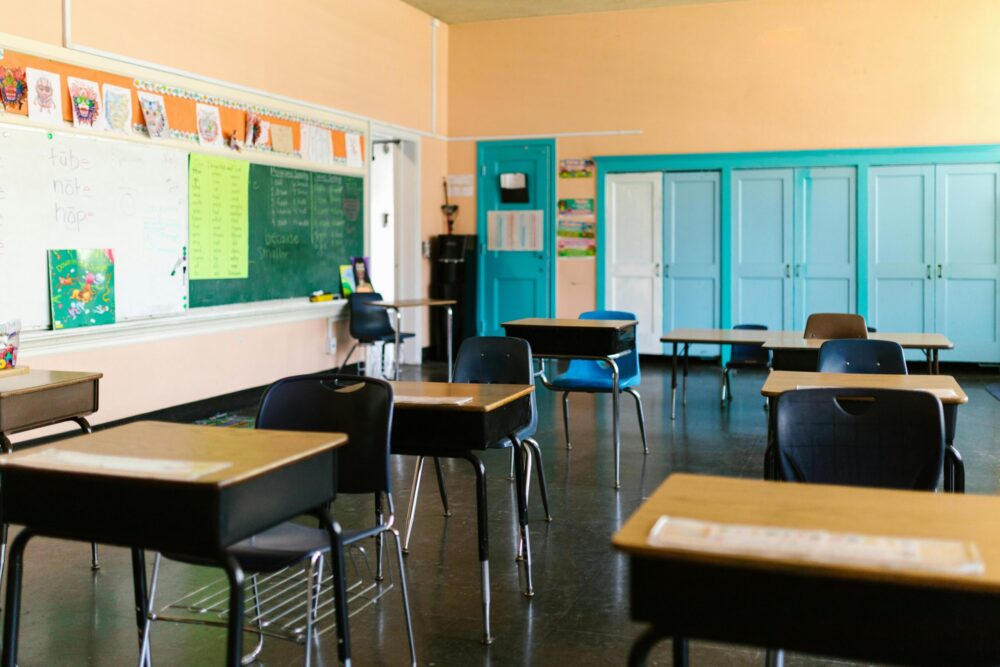 An empty classroom with desks six feet apart.