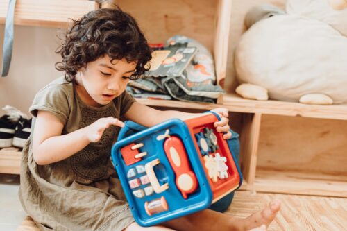 Young child sits on the floor, playing with a large toy