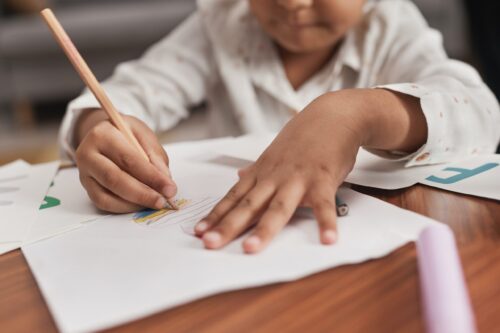 Close up of young student drawing with a colored pencil.