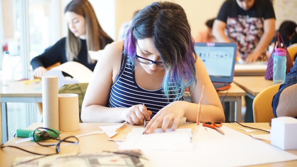 Teenage girl works on a technical project at her desk